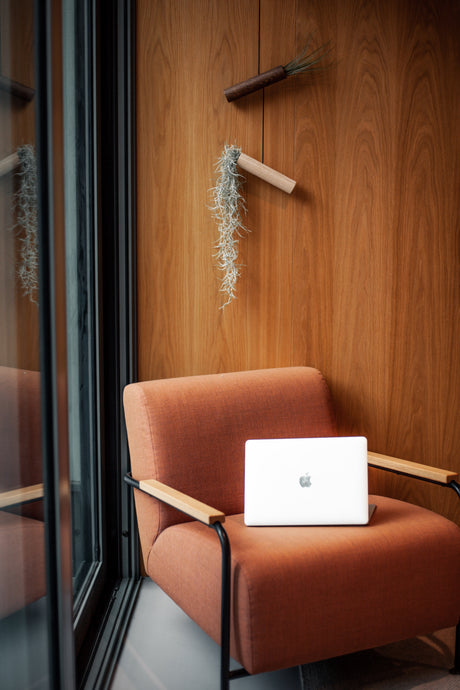 Orange armchair with a white laptop on a wooden wall background